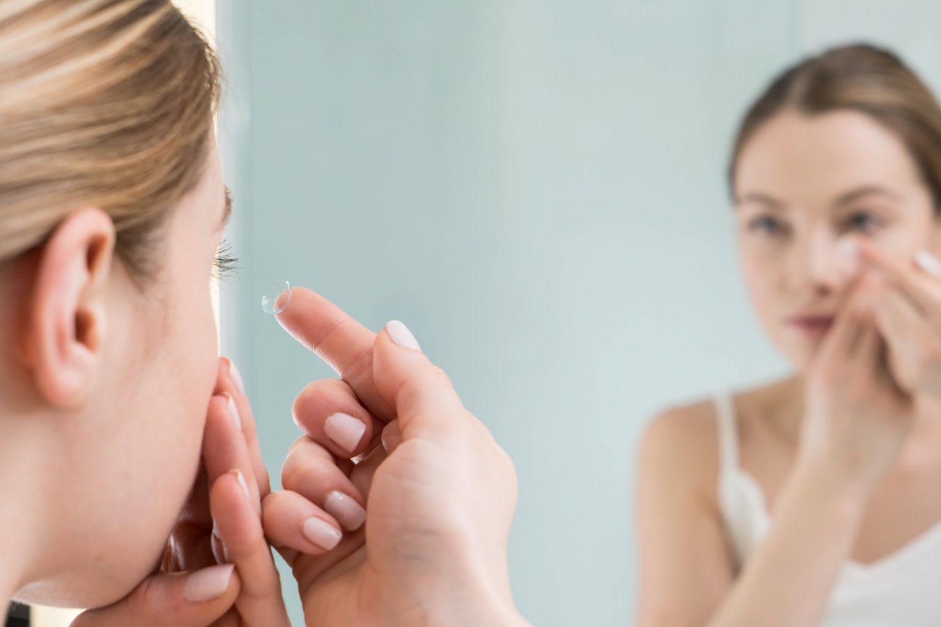 Ragazza che applica le lenti a contatto allo specchio - corretta applicazione e igiene